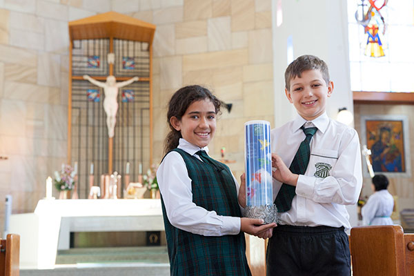 Two students holding their St Peter Chanel Catholic Primary School Regents Park school candle inside the church