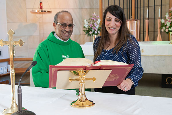 Teacher at St Peter Chanel Catholic Primary School Regents Park reading bible with Parish Priest